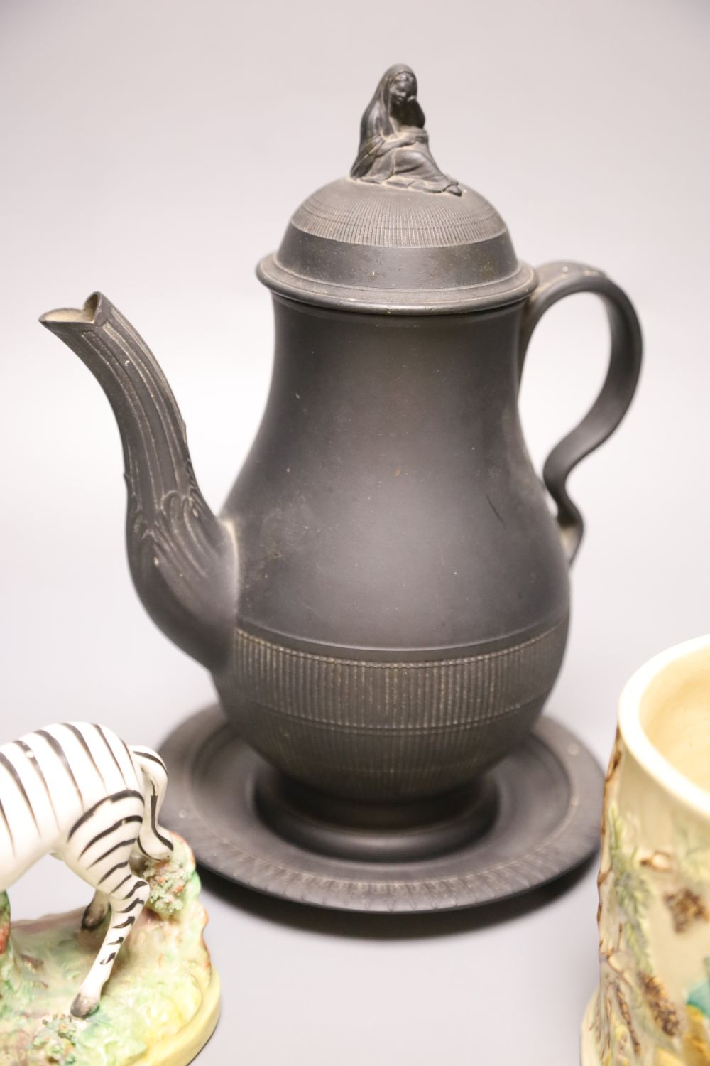 A 19th century Staffordshire pottery model of a zebra, a Victorian relief-moulded frog mug, a black basalt coffee pot with cover on sta